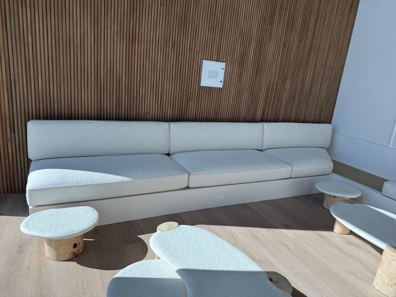 A custom-built banquette in pale linen against a walnut slat wall